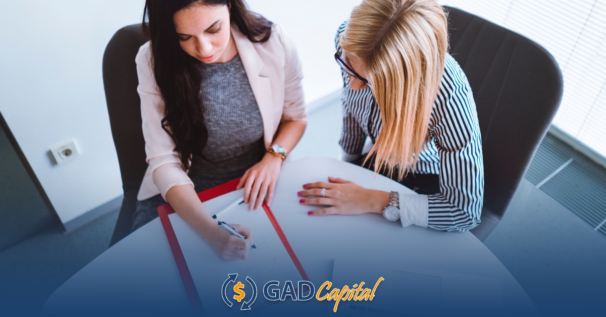 Two women sitting at a table looking at installment loans agreement paper in Colorado